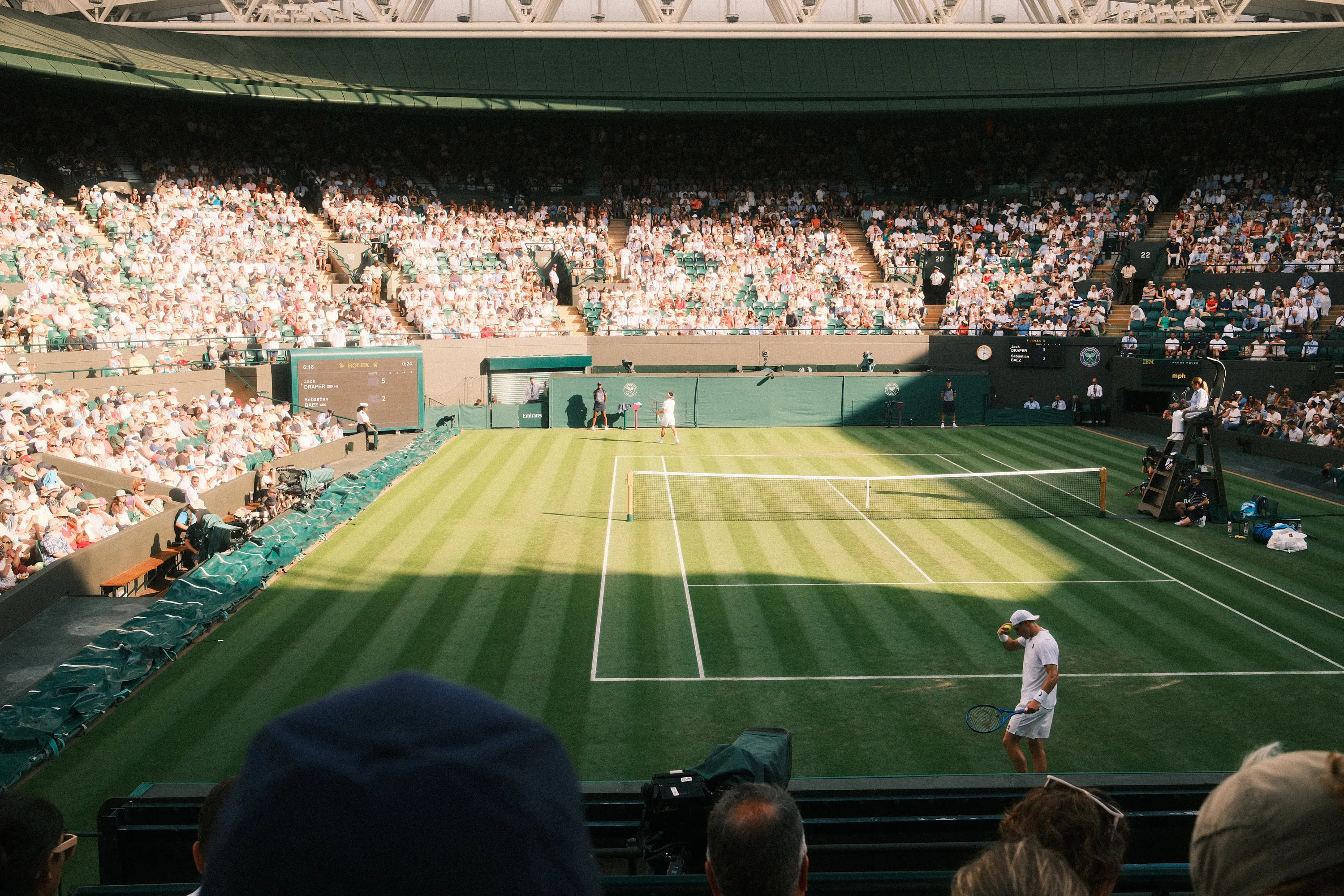 Elsewhere — Grass court, full house, late in the day.