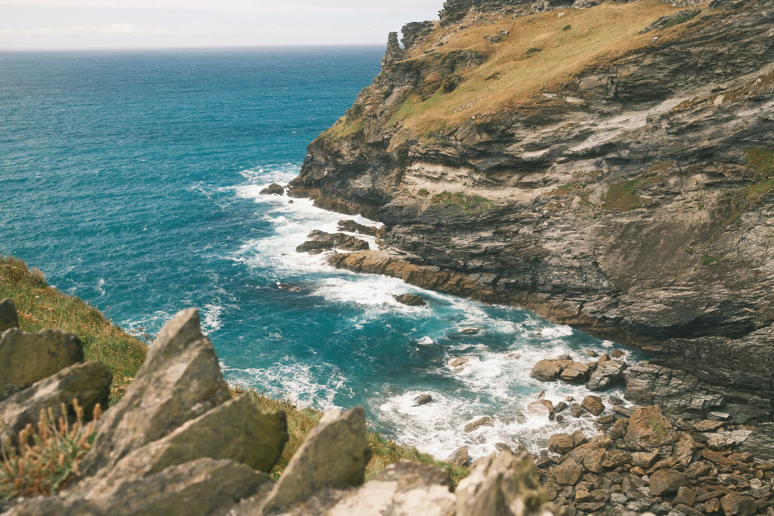 The drop to the water, surf working the rocks below.