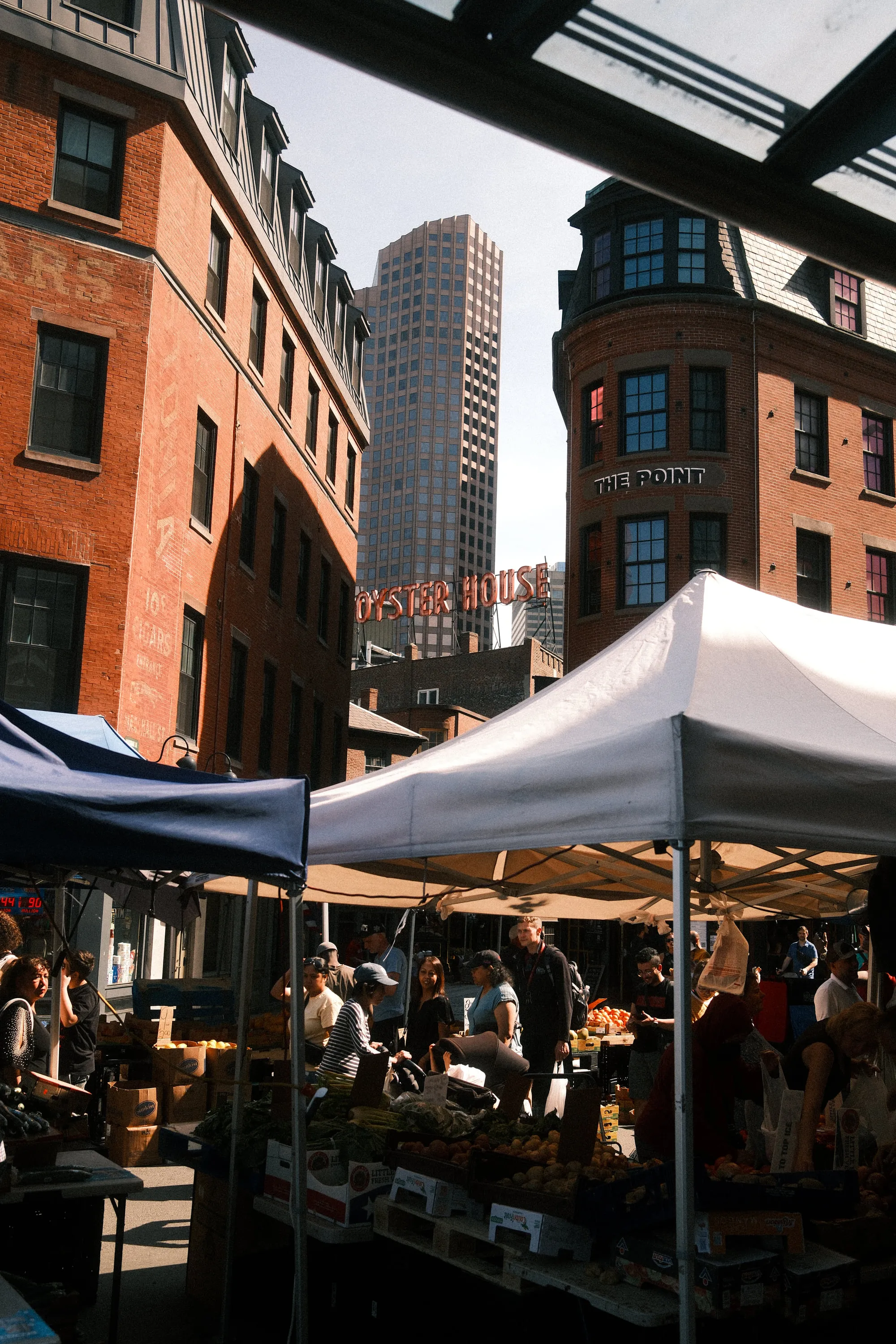 Market stalls in the gap between the old brick and the new towers.